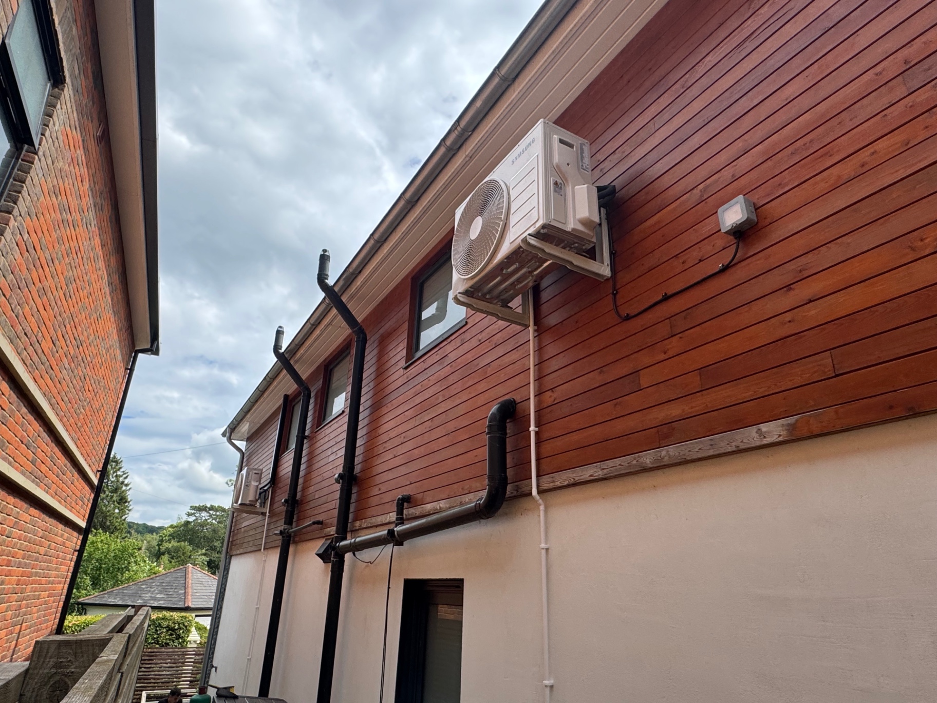Samsung outdoor condenser bracket-mounted high on timber clad wall