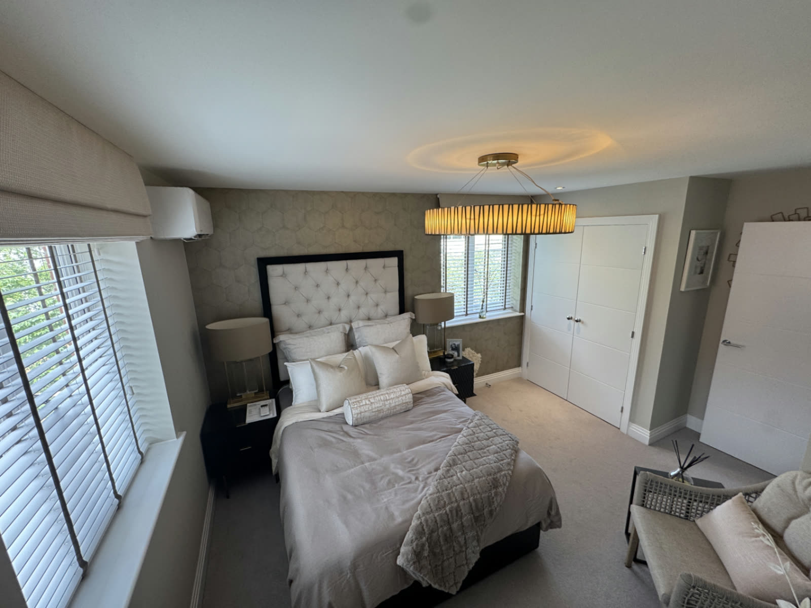 Wall-mounted air conditioning unit installed above a window in a master bedroom