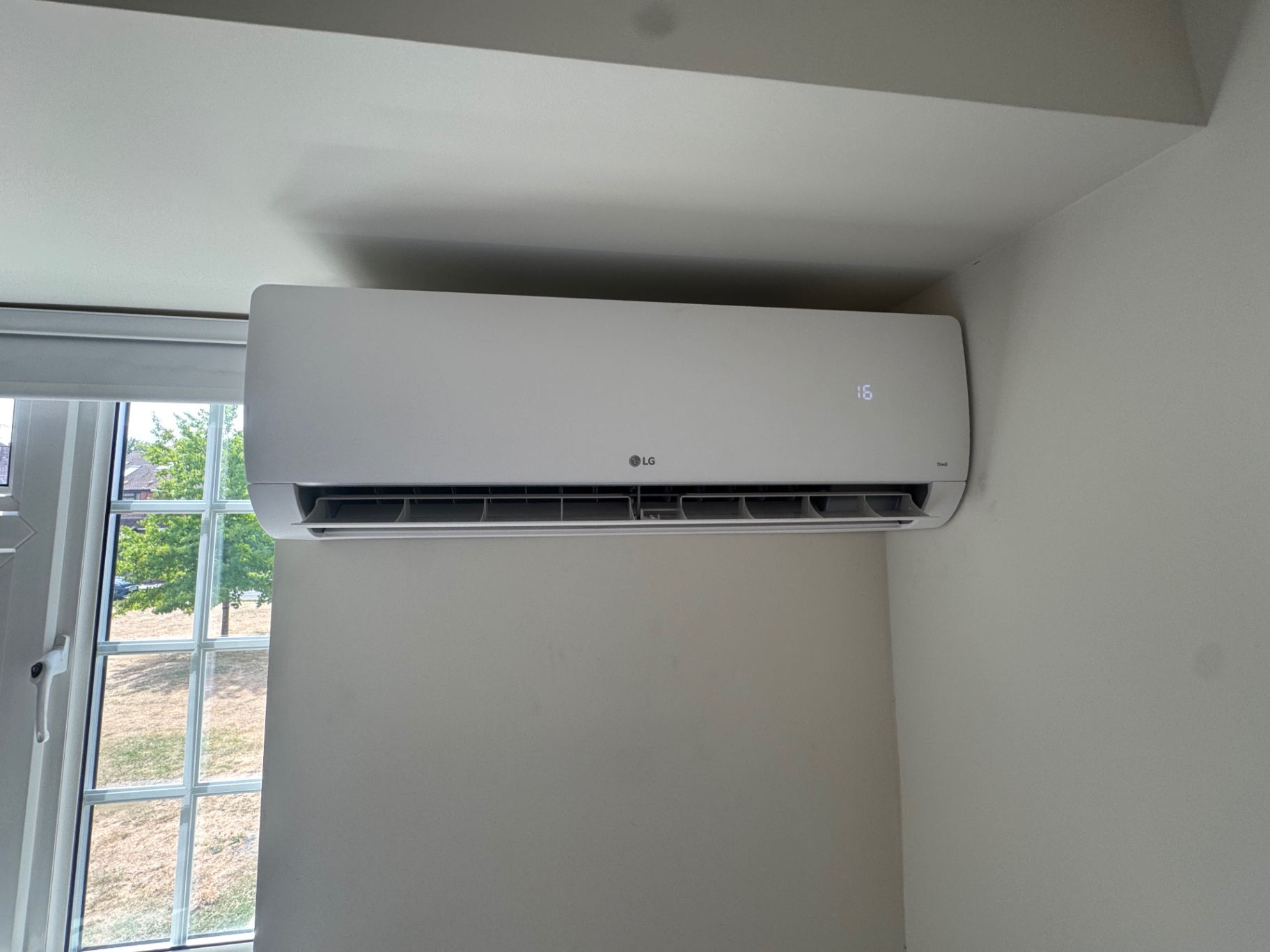 LG wall-mounted indoor air conditioning unit fitted in a bedroom