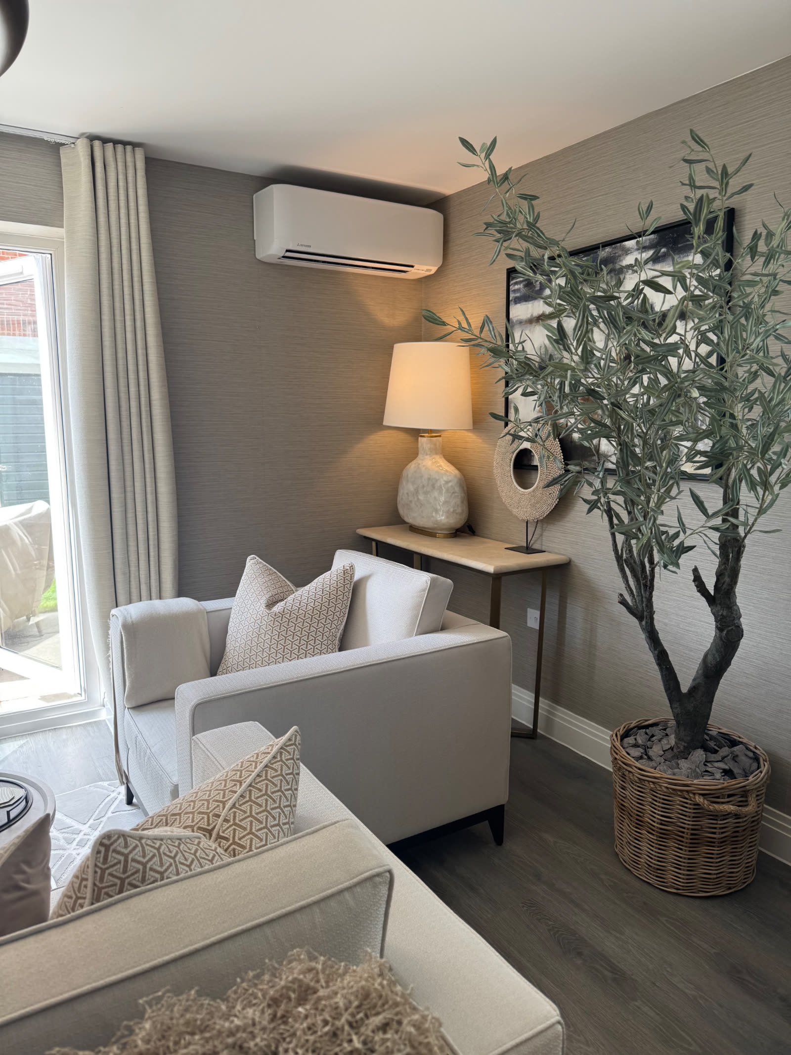 Mitsubishi Electric wall-mounted indoor unit above a sofa in a modern living room